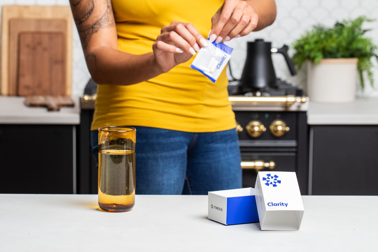 Close-up of person opening supplement sachet in modern kitchen setting.